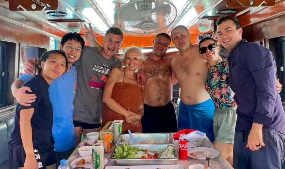 Lunchtime on a Phuket fishing tour, with guests gathered around a spread of tropical fruits and traditional dishes.
